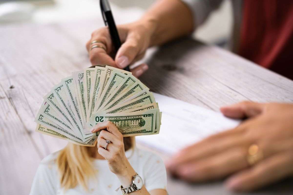 persona che firma documenti e donna con soldi