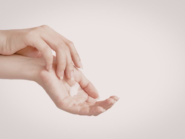 mani di donna che applicano crema