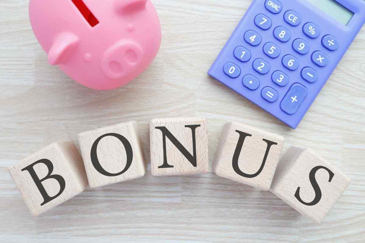scritta bonus, calcolatrice e salvadanaio a forma di maialino