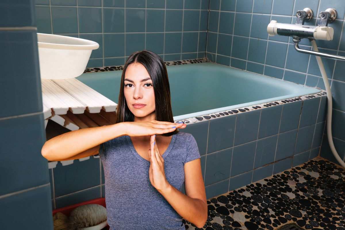 vecchio bagno e donna in primo piano che dice stop