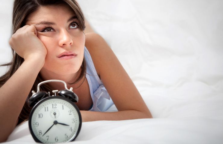 donna sveglia con orologio davanti